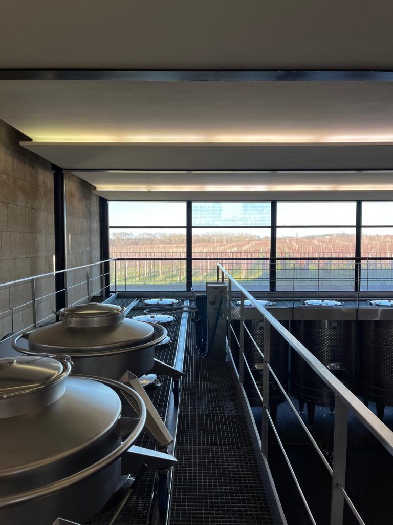 The Modern Cellar of Clinet, with its Vineyards in the Background.